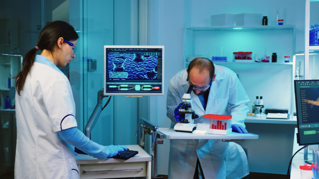 Researchers working at a fluorescence microscope workstation, representing the preclinical imaging systems used in mitochondrial peptide and mitochondria-targeted compound research.