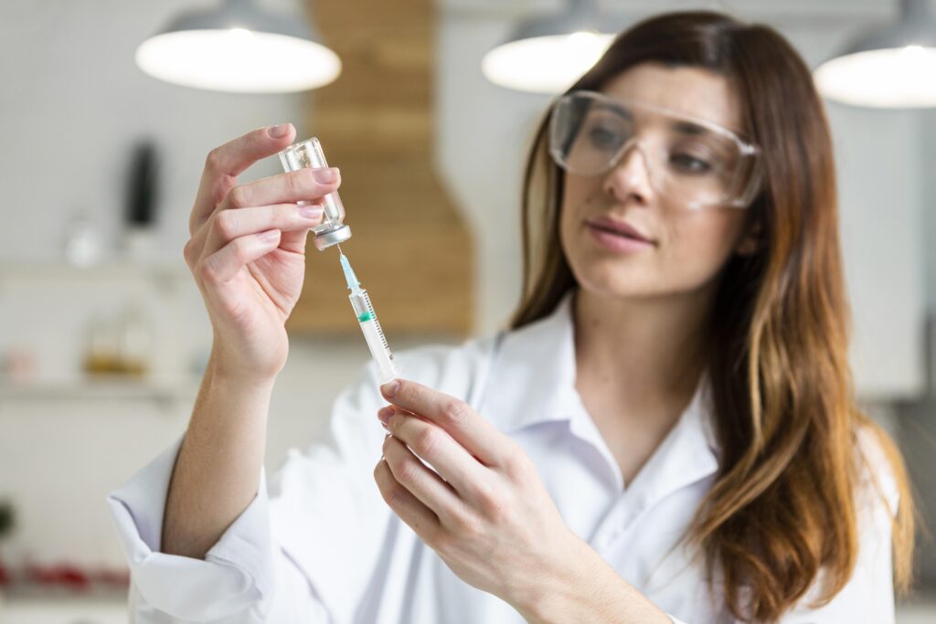 Research scientist drawing a peptide solution from a glass vial during sample preparation for growth hormone secretagogue vs. rhGH comparative assays.